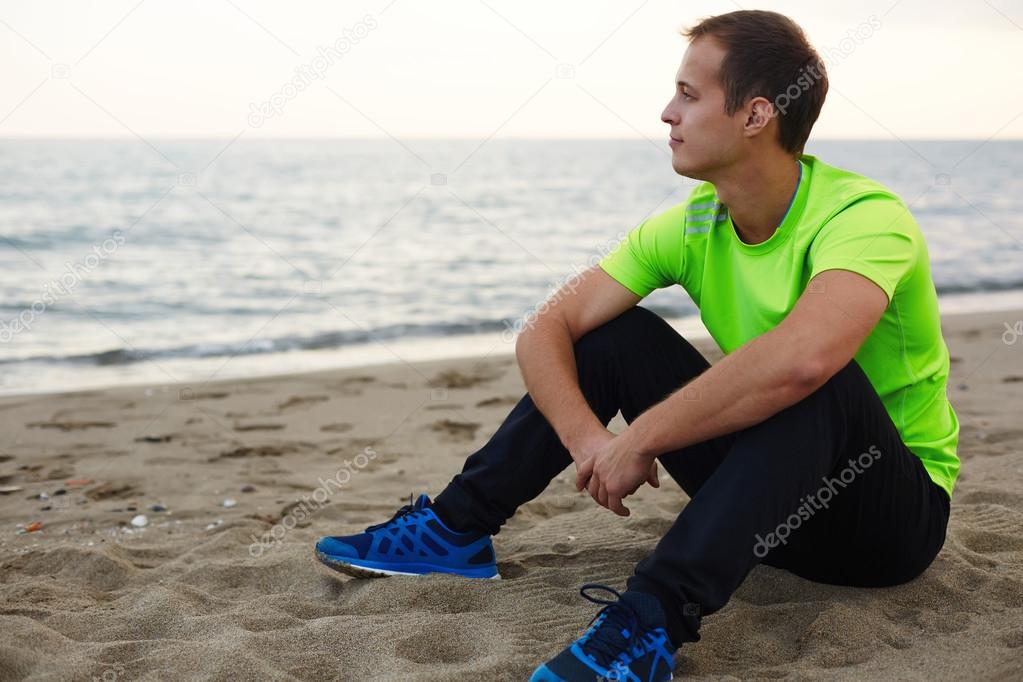 Аthlete taking break after training outdoors in amazing landscape, man relaxing outdoors