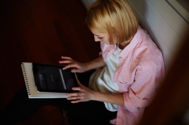 Onun dijital tablet ile evde oturan kadın