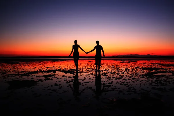 Pareja caminando de la mano en la puesta del sol — Foto de Stock