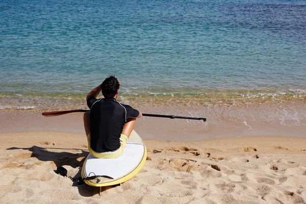 Brunett hårman sitter på stranden — Stockfoto