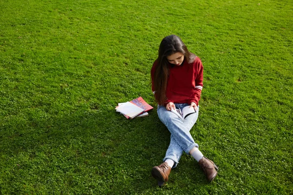 Girl sitting on the grass reading a book — Stock Photo, Image