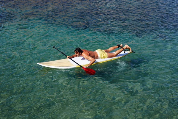 Uomo godendo di un surf in acque cristalline blu — Foto Stock