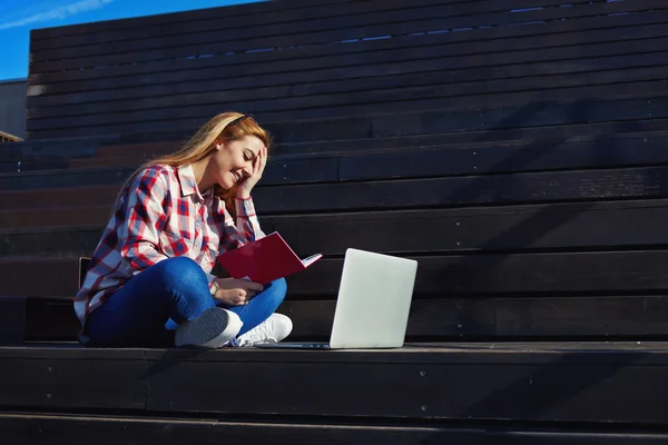Студент, обучающийся с книгой и ноутбуком — стоковое фото