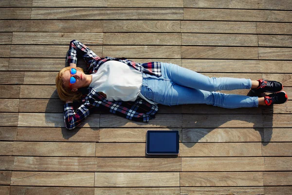 Mulher desfrutando da luz do sol enquanto deitada no cais de madeira — Fotografia de Stock