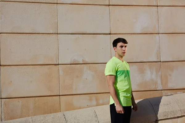 Athletic man standing against brick wall — Stock Photo, Image