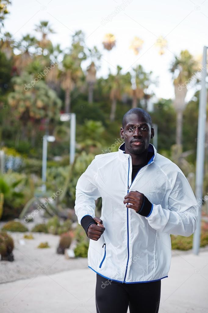 Sportive dark-skinned man jogging