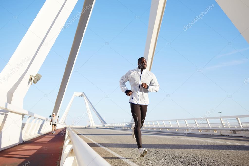 Athletic male running on a bridge