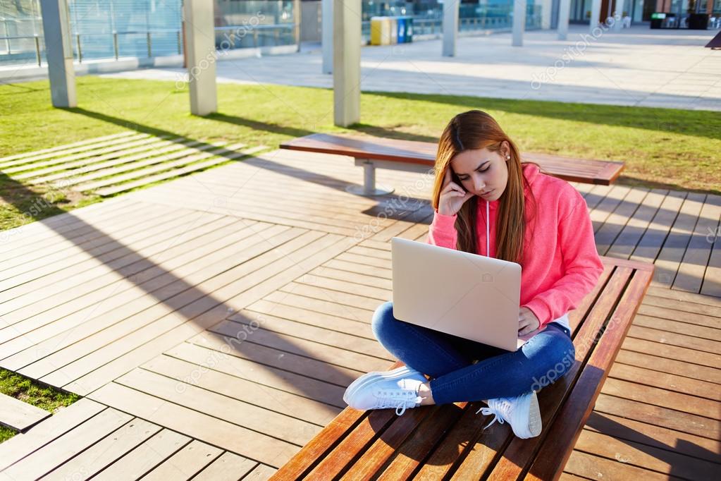 Female student focused and busy using laptop