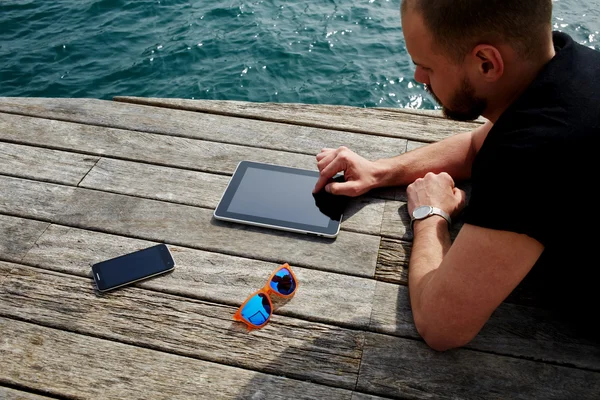 man using digital tablet near sea
