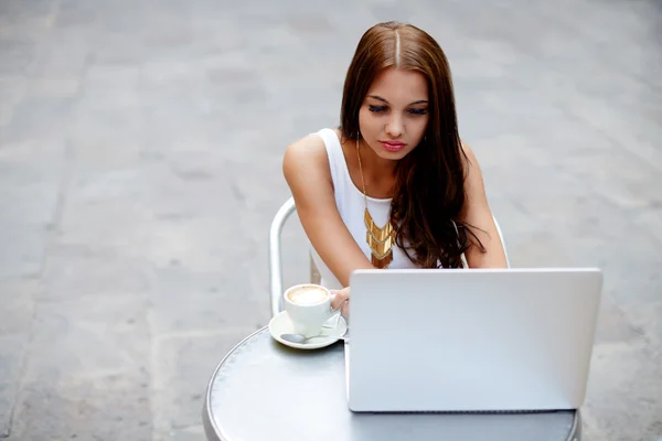 Tiener werken op haar laptop op een bistro — Stockfoto