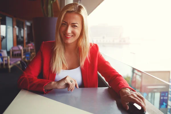Улыбающаяся элегантная женщина сидит в кафе — стоковое фото