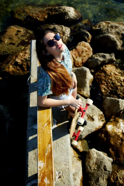 Cool vrouw poseren met skateboard in de buurt van zee — Stockfoto