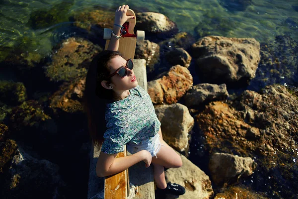 Mujer fresca posando con monopatín cerca del mar — Foto de Stock
