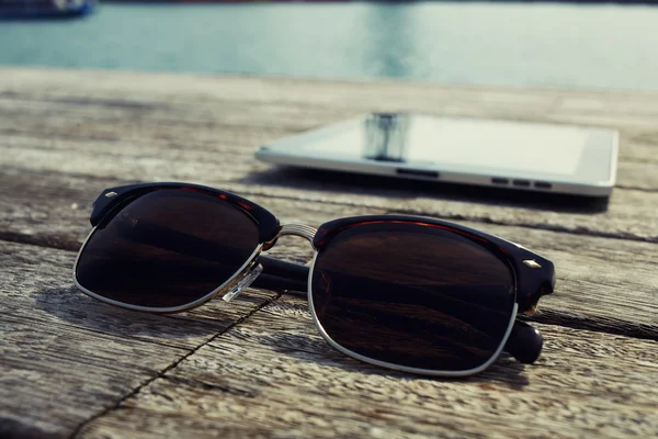 Gafas de sol y tableta digital en embarcadero de madera — Foto de Stock
