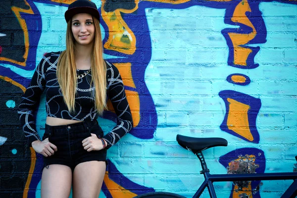 Hipster girl posing against graffiti wall — Stock Photo, Image