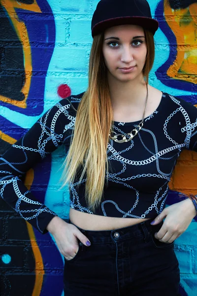 Hipster girl posing against graffiti wall — Stock Photo, Image