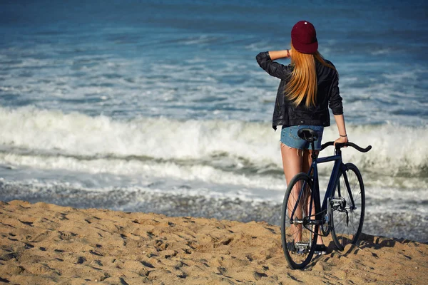 Hipster flicka avkopplande på stranden wit cykel — Stockfoto