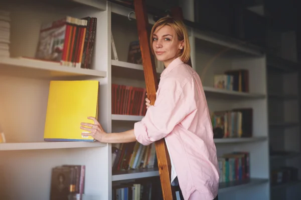 Designer with book standing on wooden ladder — Stock Photo, Image