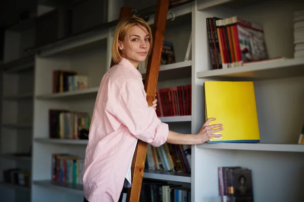 Designer com livro em pé na escada de madeira — Fotografia de Stock