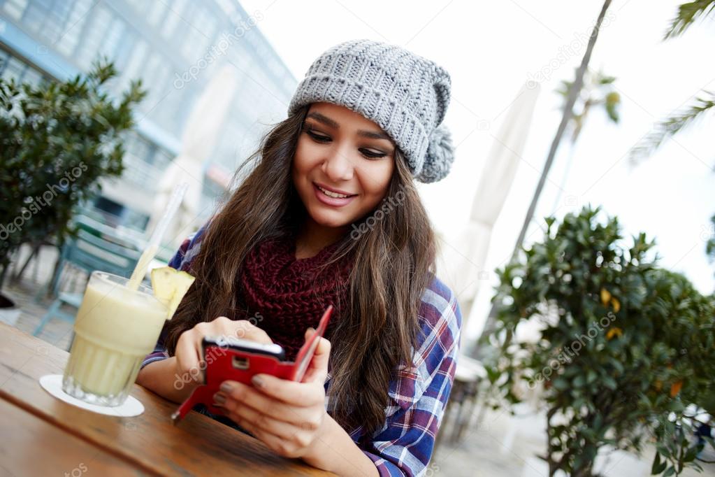 woman sending text message from cafe