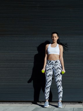 ağırlıklar ile eller aşağı tutan kadın