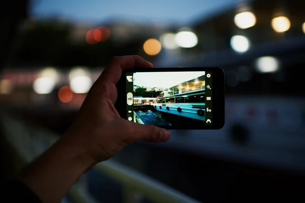 Mão com smartphone atirando cidade noite — Fotografia de Stock