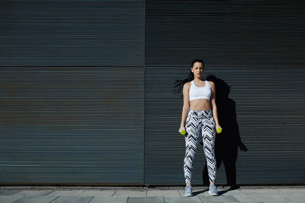 Woman holding weights with hands down — Stock Photo, Image