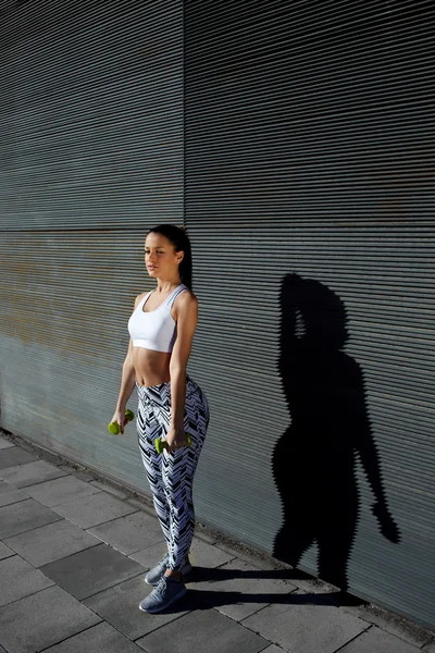 Woman holding weights with hands down — Stock Photo, Image