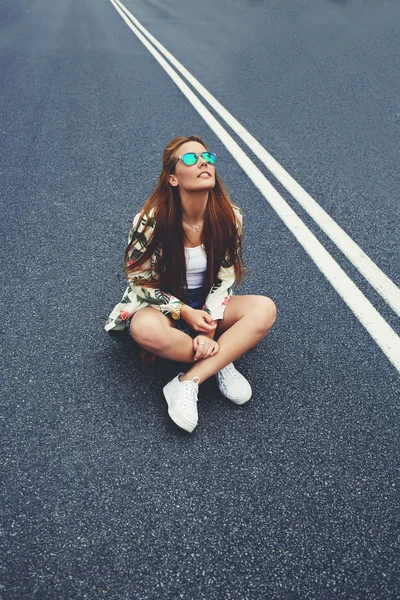 Hipster chica sentado en el medio de asfalto carretera — Foto de Stock