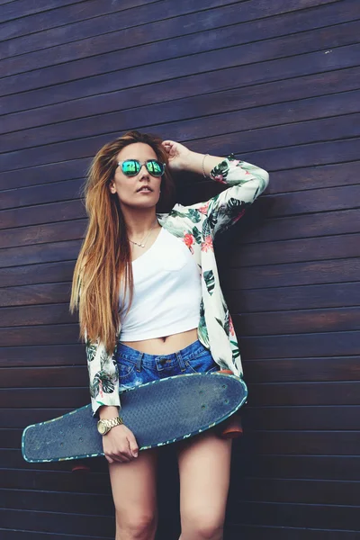 Adolescente chica en gafas de sol celebración de monopatín — Foto de Stock