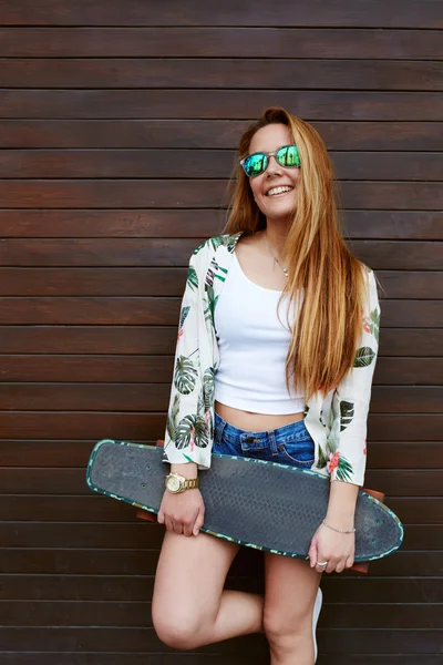 Adolescente em óculos de sol segurando skate — Fotografia de Stock