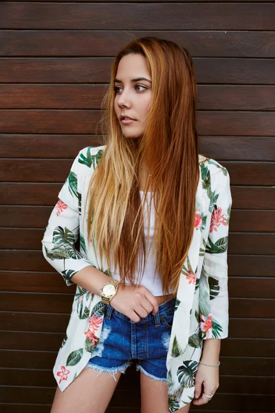 Mujer joven de pie contra la pared de madera — Foto de Stock