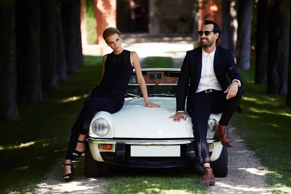 Modisches Paar posiert auf Luxusauto — Stockfoto