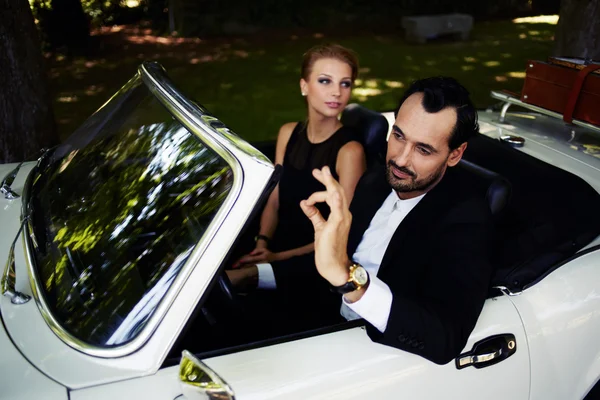 Wealthy and famous couple sitting inside cabriolet — Stock Photo, Image