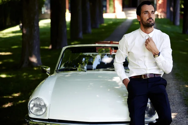 Homem sentado no capô de luxo cabriolet — Fotografia de Stock