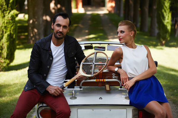 супружеская пара, опирающаяся на старинный автомобиль
