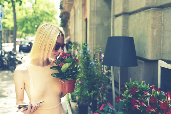 Mujer oliendo flores mientras compra plantas — Foto de Stock