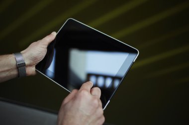 Cropped shot of male person holding digital tablet with beautiful reflection on the screen