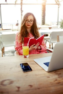 Young female woman having breakfast on terrace in modern coffee shop
