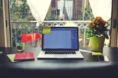 The laptop is on the table in front of an open window