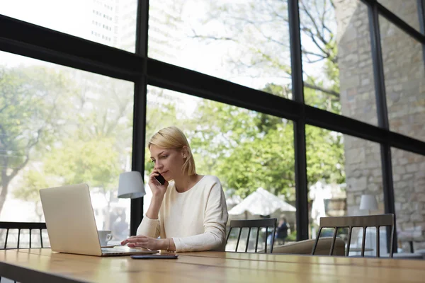 Jeune femme d'affaires utilisant un ordinateur portable et un smartphone — Photo