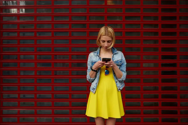 Studente hipster femminile in abito utilizzando il telefono cellulare per connettersi al wireless — Foto Stock