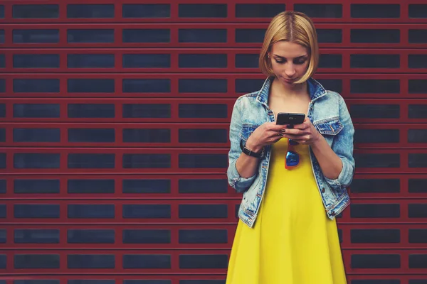 Hübsche junge Frau chattet auf ihrem Smartphone vor leerem Kopierraum hellen Hintergrund für Ihre Inhalte oder SMS — Stockfoto