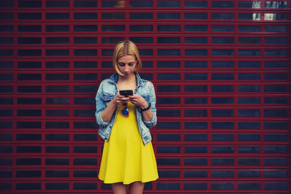 Estudiante hipster femenino en el vestido usando el teléfono móvil para conectarse a inalámbrico —  Fotos de Stock