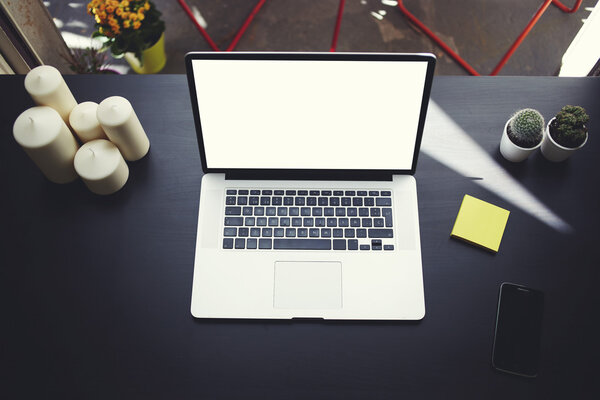 The laptop is on the table in front of an open window