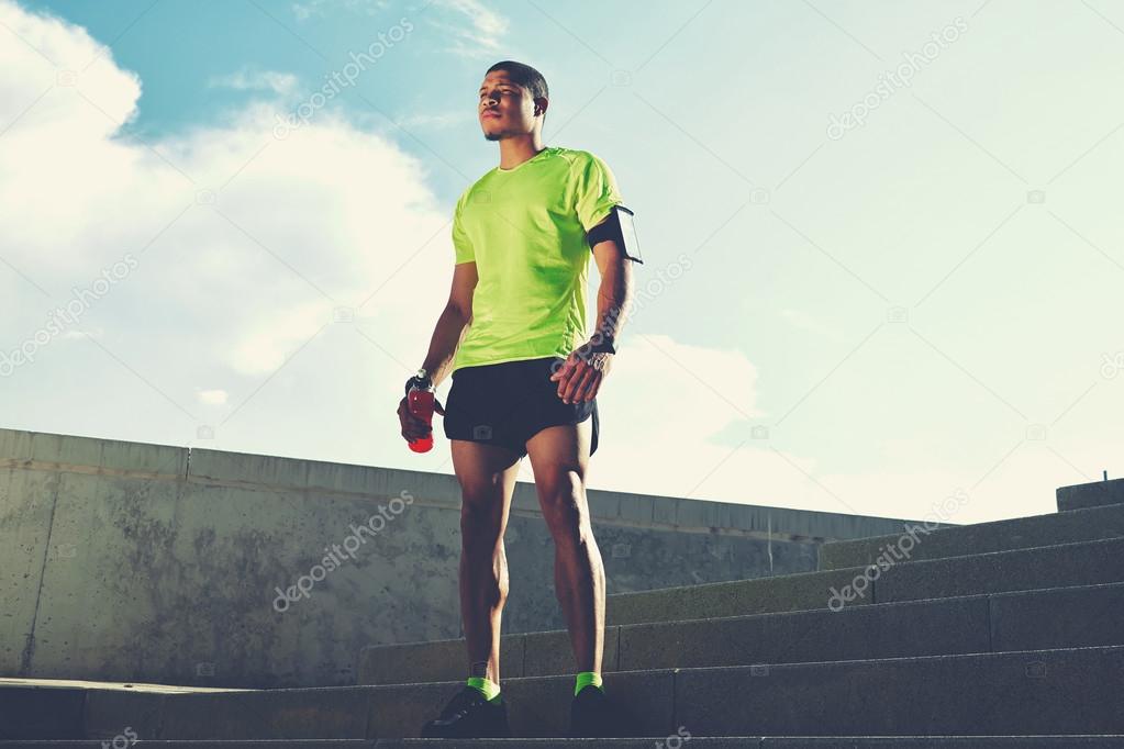 male runner in bright t-shirt resting
