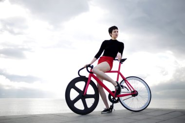 Young female hipster standing with bicycle