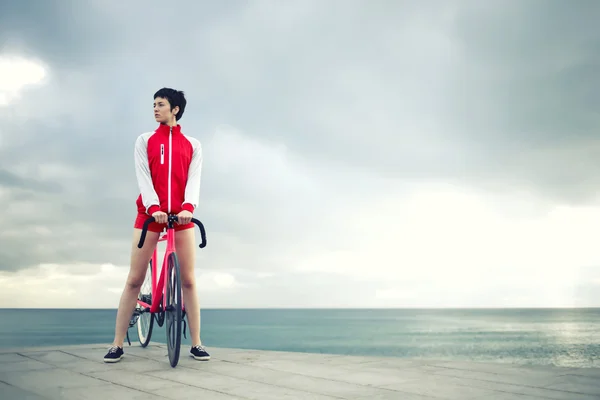 Female cyclist standing with her bicycle — Stock Photo, Image