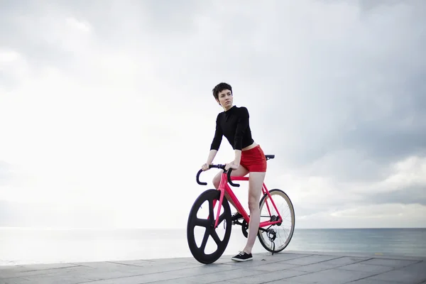 Стильна жінка стоїть на пірсі з велосипедом — стокове фото