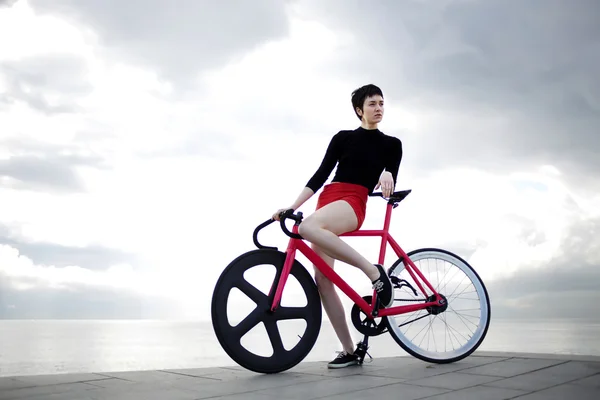 Young female hipster standing with bicycle — Stockfoto